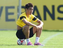 Shinji Kagawa zit op een bal tijdens de training van Borussia Dortmund. (03-09-2014)