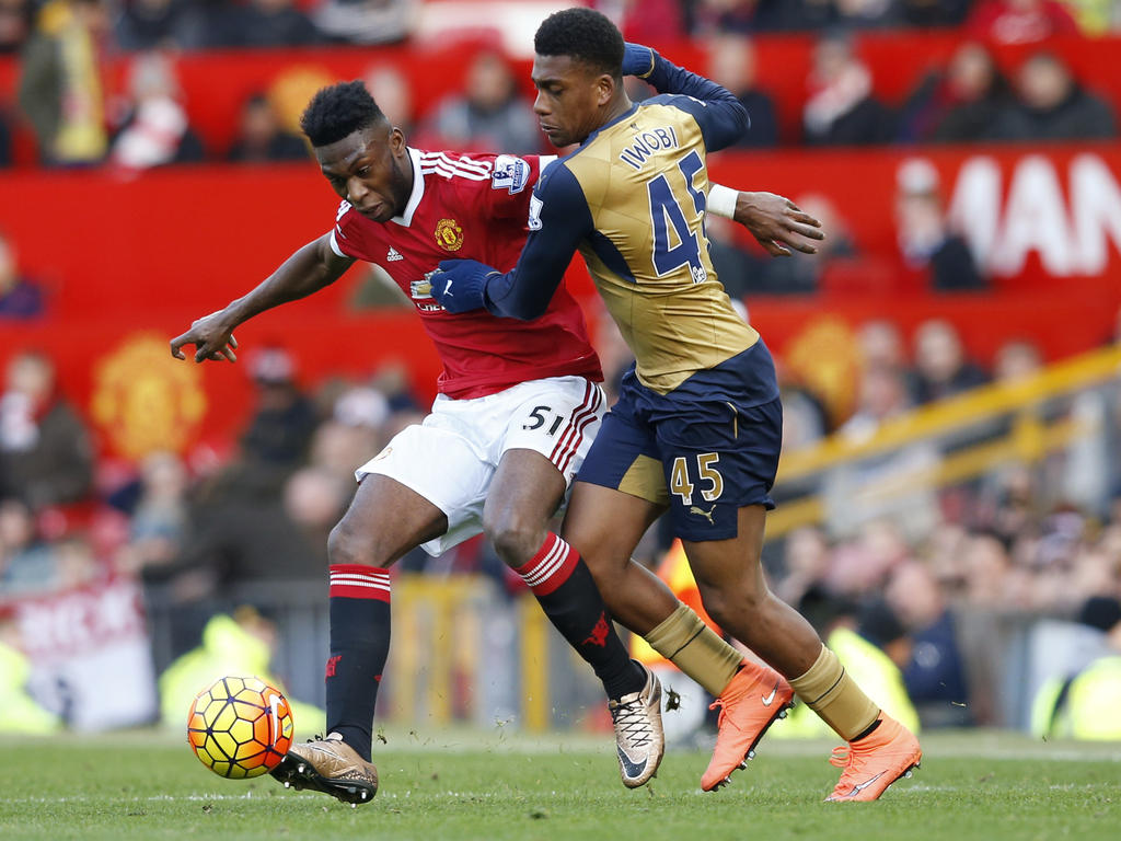 Timothy Fosu-Mensah (l.) is tijdens zijn debuut voor Manchester United in duel met Arsenal-speler Alex Iwobi (r.). (28-02-2016)