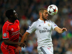 Liverpool-verdediger Kolo Touré (l.) kan alleen maar toekijken hoe Real Madrid-spits Karim Benzema (r.) de bal met zijn hoofd controleert in de groepsfase van de Champions League. (04-11-2014)