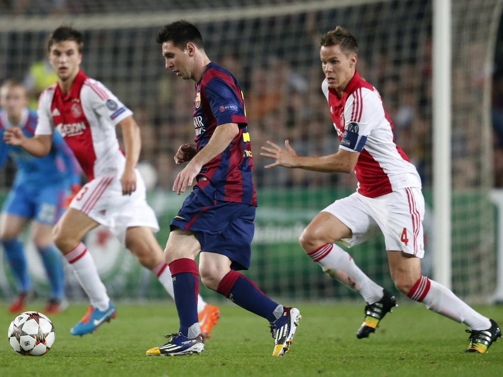 Niklas Moisander (r.) probeert Lionel Messi (m.) af te stoppen tijdens FC Barcelona - Ajax. (21-10-2014)