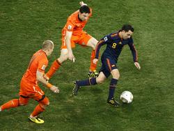 Xavi Hérnandez (r.) dribbelt voorbij Arjen Robben (l.) en Mark van Bommel (m.). De Spanjaard houdt de bal dicht bij zich. (06-07-2010)
