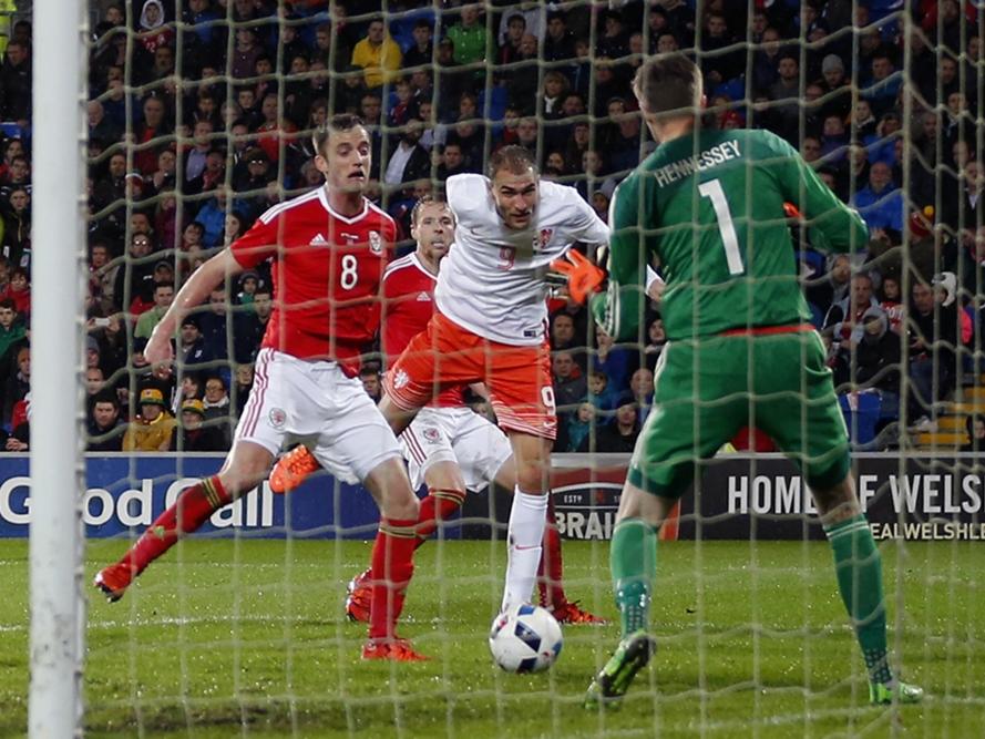 Bas Dost (m.) krijgt veel vrijheid bij de tweede paal na een voorzet en de spits kopt raak voor zijn eerste goal in het shirt van het Nederlands elftal. Wayne Hennessey (r.) wordt verschalkt, Nederland komt op een 0-1 voorsprong. (13-11-2015)