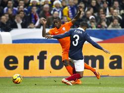 Debutant Quincy Promes (l.) is de ervaren verdediger Patrice Evra (r.) te snel af tijdens Frankrijk - Nederland. (5-3-2014)