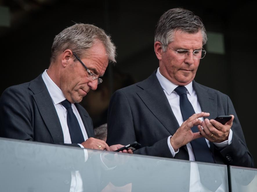 Algemeen directeur Eric Gudde (l.) en technisch directeur Martin val Geel (r.) kijken tijdens PSV - Feyenoord even op hun telefoon. (30-08-2015)