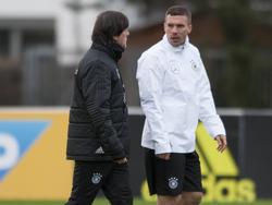 Lukas Podolski (r.) praat tijdens de training van de nationale ploeg van Duitsland met bondscoach Joachim Löw (l.) (21-03-2017).