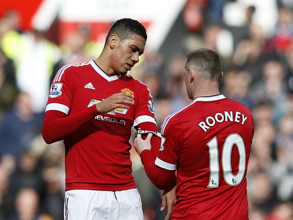 Wayne Rooney (r.) schuift zijn aanvoerdersband om de arm van Chris Smalling (l.) tijdens het competitieduel Manchester United - Aston Villa (16-04-2016). Wayne Rooney (r.) schuift zijn aanvoerdersband om de arm van Chris Smalling (l.) tijdens het competitieduel Manchester United - Aston Villa (16-04-2016).