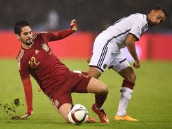 Spanjaard Isco (l.) glijdt zich voor de bal in een poging de bal te veroveren van Karim Bellarabi (r.) in het vriendschappelijke duel tegen Duitsland. (18-11-2014)