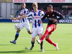 Excelsior-speler Brandley Kuwas (r.) geeft een voorzet terwijl SC Heerenveen-verdediger Joost van Aken (m.) de aanvaller op de huid zit. Op de achtergrond kijkt Kenneth Otigba toe hoe zijn ploeggenoot de situatie probeert op te lossen.