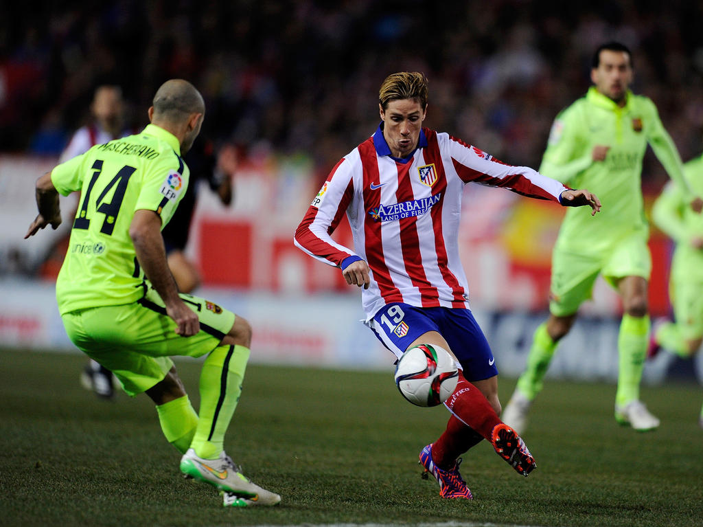 Fernando Torres (m.) van Atlético Madrid met een actie ten Javier Mascherano (l.) van FC Barcelona. (28-01-2015)