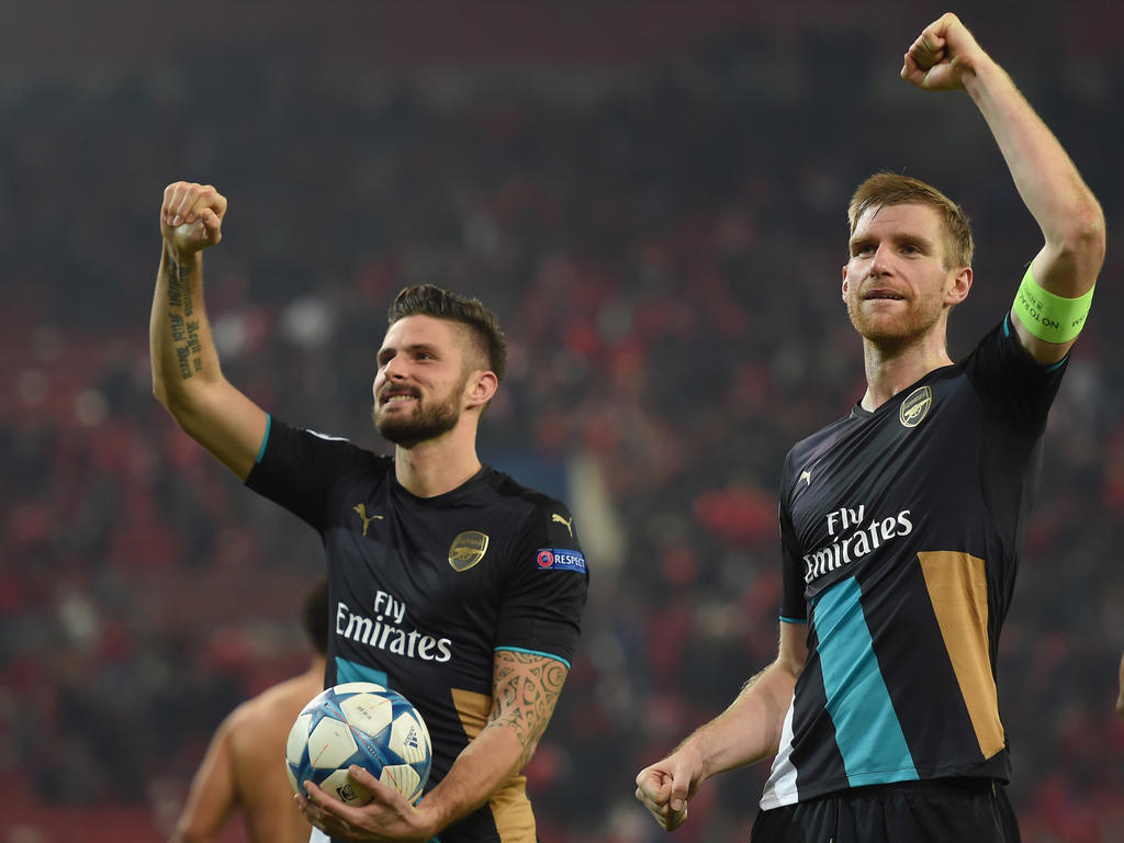 Hattrick-Schütze Olivier Giroud und Per Mertesacker bejubeln Arsenals fast schon zur Tradition gewordenen Aufstieg in die K.o.-Phase der Champions League.