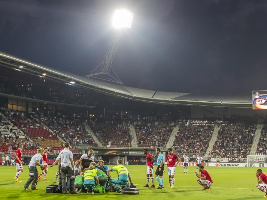 Spelers van AZ kijken verschrikt toe hoe Stijn Wuytens (l.) door medisch personeel wordt behandeld. De Belg van AZ botst met de goalie van Dundalk en blijft vervolgens roerloos liggen. (15-09-2016)