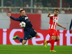 Manchester United-aanvaller Wayne Rooney (l) vliegt richting de bal in het Champions League-duel met Olympiakos Piraeus. Giannis Maniatis (r) kijkt toe. (25-2-2014)