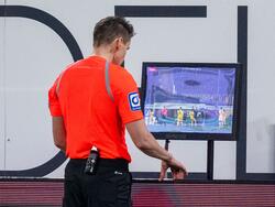 Schiedsrichter Daniel Siebert überprüft ein Handspiel per Videobeweis