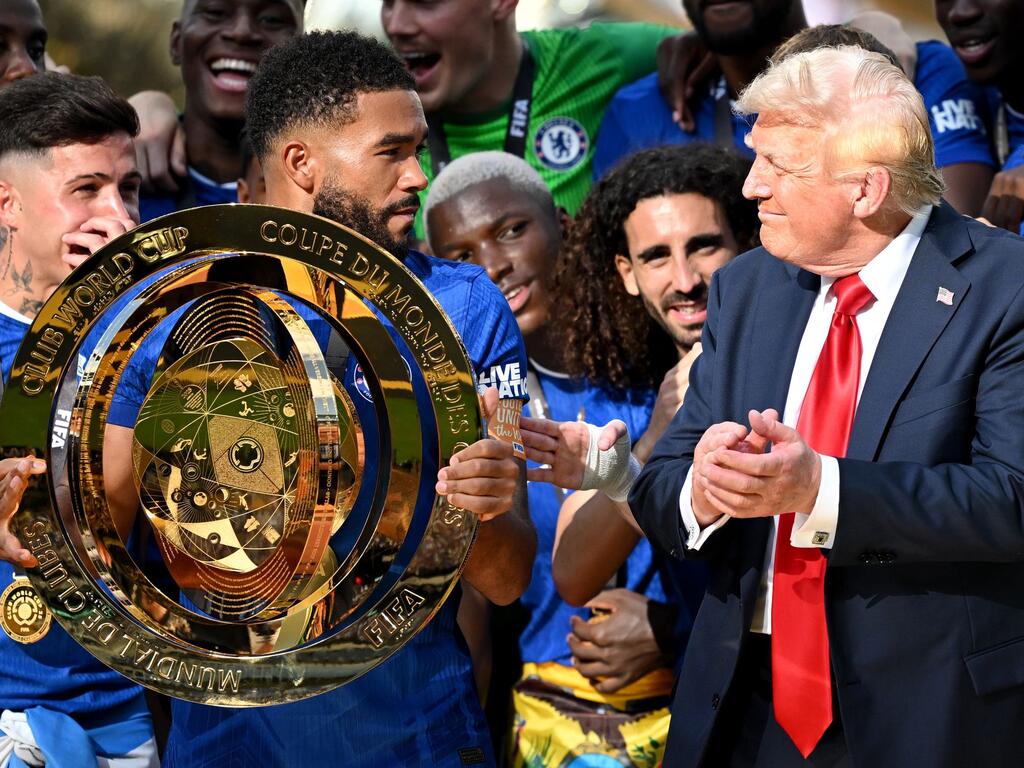 Chelseas Kapitän Reece James (l/vorn) hält auf dem Siegerpodest die Trophäe in den Händen und schaut irritiert zu US-Präsident Donald Trump