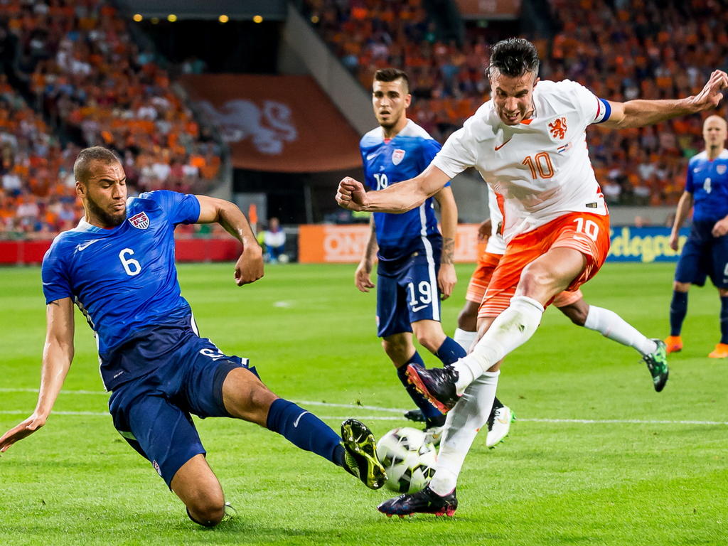 Robin van Persie schiet de bal richting het doel van Brad Guzan, maar John Brooks ligt in de weg. (05-06-2015)