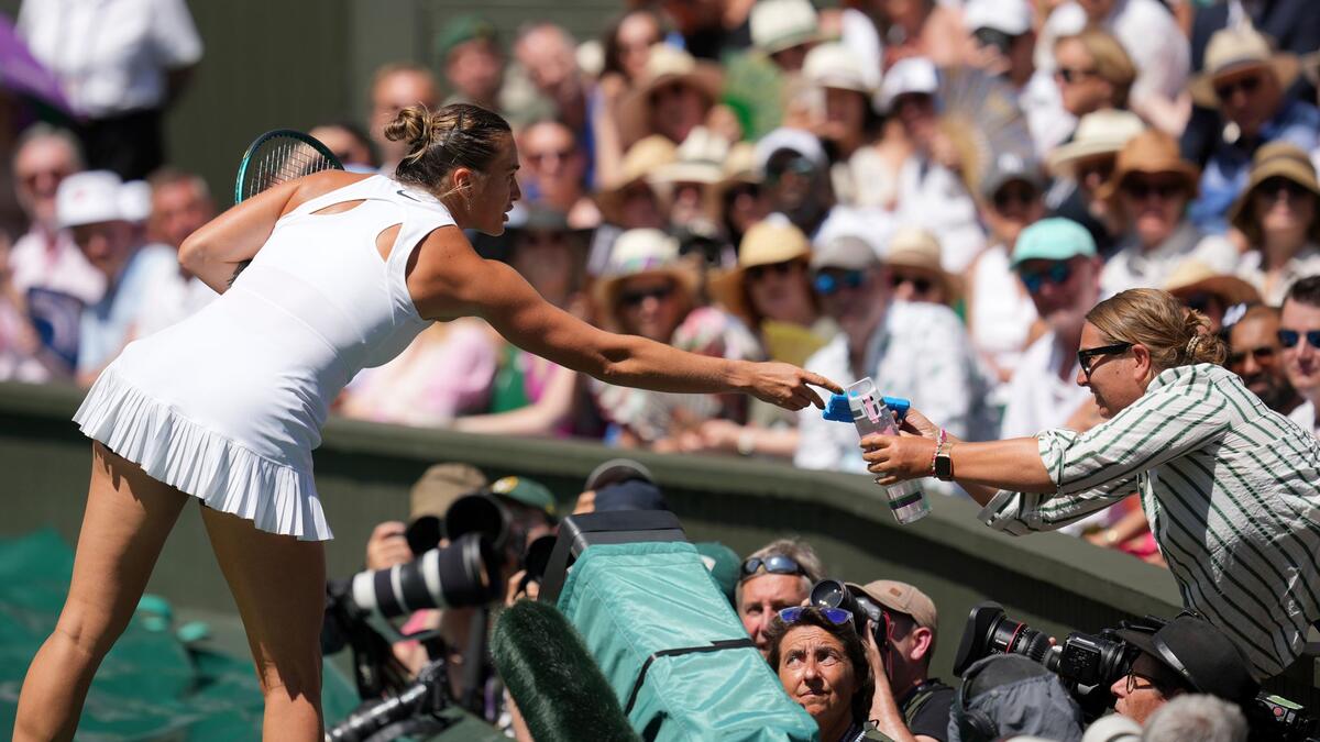 Aryna Sabalenka reicht eine Flasche Wasser und ein Kühlpack auf die Tribüne