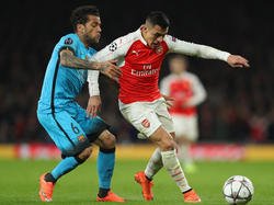 Dani Alves (l.) probeert tijdens het Champions League-treffen tussen Arsenal en FC Barcelona Alexis Sanchéz (r.) van de bal te krijgen. (23-02-2016)