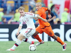 Deen Christian Eriksen schudt Oranje-middenvelder Nigel de Jong van zich af op het EK 2012. (09-06-2012)